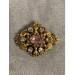 An unmarked yellow metal topaz and amethyst brooch with free cut oval topaz