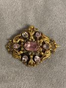 An unmarked yellow metal topaz and amethyst brooch with free cut oval topaz