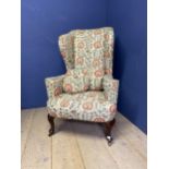 A high backed, Queen Anne style winged arm chair, upholstered in a tapestry/needlepoint design