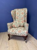 A high backed, Queen Anne style winged arm chair, upholstered in a tapestry/needlepoint design