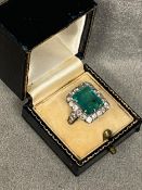 A platinum diamond and emerald ladies dress ring, central 5 ct emerald in 8 claw setting, with a