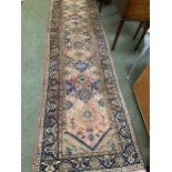 A rug, with orange ground and all over stylized patters, runner 105 x 388cm