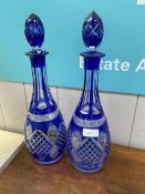 A pair of tall decanters, the glass decorated with blue insert panels and stoppers