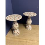 A pair of floral decorated pedestal and circular top ceramic side tables