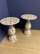 A pair of floral decorated pedestal and circular top ceramic side tables