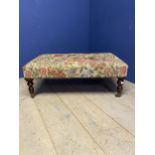 A square low Foot stool, upholstered in a floral fabric on turned legs and castors