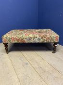 A square low Foot stool, upholstered in a floral fabric on turned legs and castors