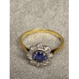 18ct gold and platinum Sapphire and diamond flower ring, central free cut oval saphire with surround