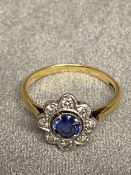 18ct gold and platinum Sapphire and diamond flower ring, central free cut oval saphire with surround