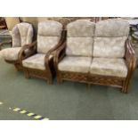 A dark brown cane sofa and chair suite, with loose cushions, tilting and revolving arm chair