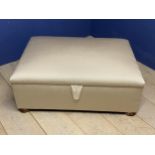 A good cream upholstered ottoman, with rising lid to reveal storage, on 4 wooden bun feet