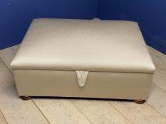 A good cream upholstered ottoman, with rising lid to reveal storage, on 4 wooden bun feet