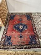 Persian burgundy ground Rug, with blue central lozenge and corner lozenges, and multi border 230cm x