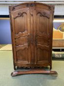 A large French style fruitwood two door, carved Armoire, the top pediment off and with some wear,
