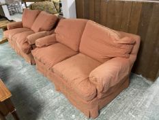Pair of two seater, upholstered sofas, in a patterned salmon pink fabric, loose covers. Consigned