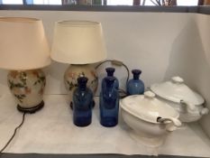 Two lamps, a pair of white lidded tureens with ladles, and a 4 large glass bottles with stoppers