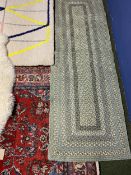 Persian rug, red ground with cream and blue multi stylized borders and a Ikea rug, sheepskin style