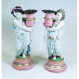 A pair of late Victorian figural porcelain candlesticks, each in the form of a child holding a