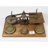 A set of brass Post Office scales and weights, on an oak plinth