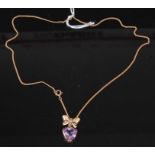 A 9ct yellow gold and amethyst pendant, having a heart shaped amethyst suspended from a bow and
