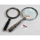 A large magnifying glass, the white metal handle relief decorated with various figures and