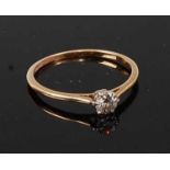 A yellow and white metal diamond single stone ring, the round brilliant cut diamond in a six-claw