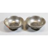 A pair of Chinese white metal shallow bowls, the exteriors relief decorated with various figures and