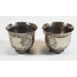 A pair of Eastern white metal cups, each having flared rim and embossed roundel, to a circular