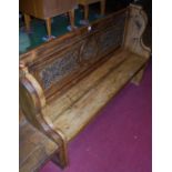 A stained planked pine panelled back four-seater settle, the panel floral relief decorated, w.150cm