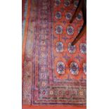 A large Persian style machine-woven red ground Bokhara rug, 335 x 239cm