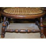 An early 20th century oak and cane topped oval low stool, w.43cm