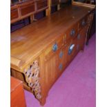 A Chinese elm sideboard, having three frieze drawers over conforming twin cupboard doors, with brass