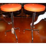 A pair of 1960s retro tubular chrome and orange vinyl topped circular low bar stools, each h.
