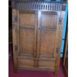 A 17th century style joined and panelled oak double door side cupboard, having exposed iron