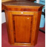 An early 19th century oak and mahogany crossbanded single door hanging corner cupboard, w.82cm