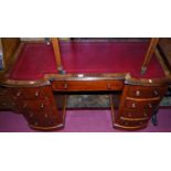A Victorian mahogany inverted breakfront kneehole pedestal writing desk, having a gilt tooled red