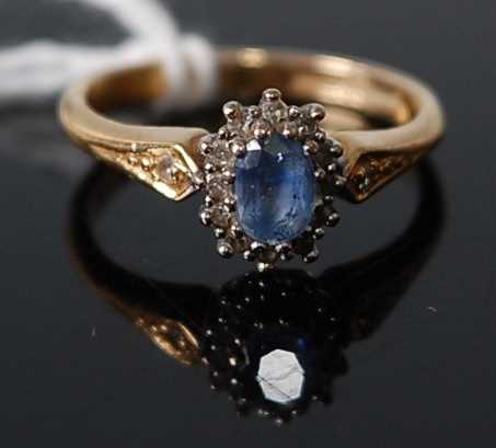 An 18ct yellow and white gold, sapphire and diamond oval cluster ring, the centre sapphire measuring