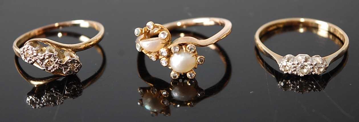 Three rings, comprising a yellow and white metal diamond three-stone ring, having three round