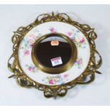 A brass and china wall mirror, with central convex plate, mounted on a ceramic plate by Royal