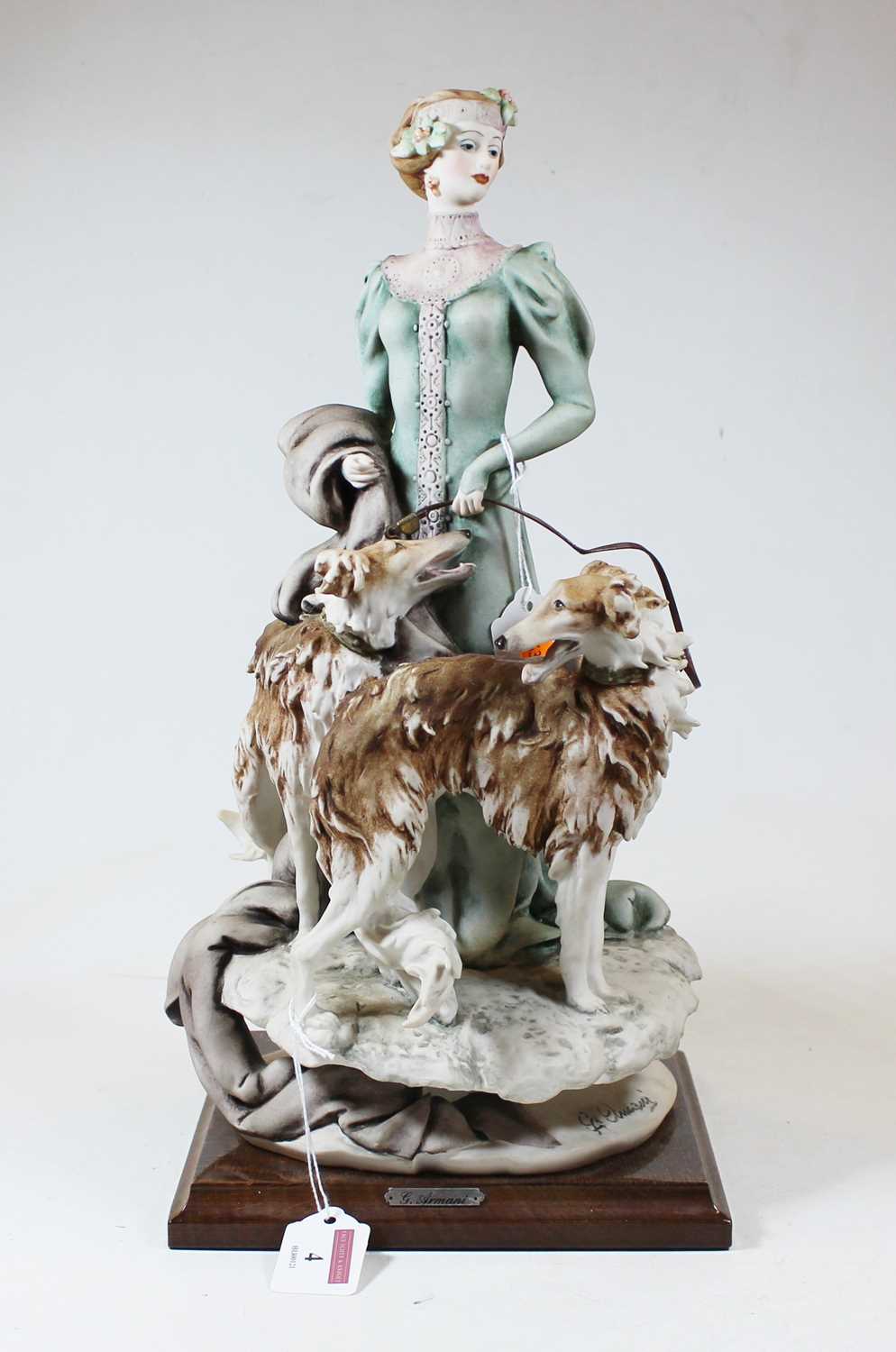 An Italian bisque figure of a Lady with two dogs by Giuseppe Armani, mounted on a moulded wooden