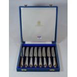 A set of eight cheese knives, each having a steel blade and white metal handle, in fitted Garrard'