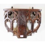 A Victorian carved oak wall bracket, the apron with pierced early English Gothic style carved