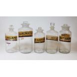 A collection of five various 19th century clear glass apothecary jars and stoppers, each bearing a