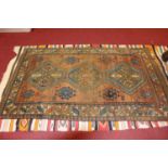 An Afghan woollen rug, the brown ground decorated with three linked medallions within gul motifs and