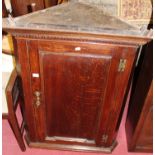 An early 19th century oak single door hanging corner cupboard