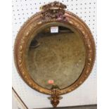 A 19th century giltwood oval wall mirror, having raised fruiting vine border with floral upper and