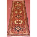A Turkish woollen hall runner, having a rust coloured field decorated with seven medallions, 69 x