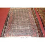 A Persian woollen rug, the blue ground decorated with five rows of stylised motifs and guls,