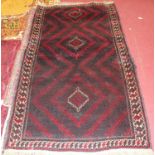 A Turkish woollen rug, the rust coloured ground decorated with three lozenge medallions and having