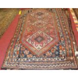 A Turkish woollen rug, the central ground decorated with three linked lozenge medallions,